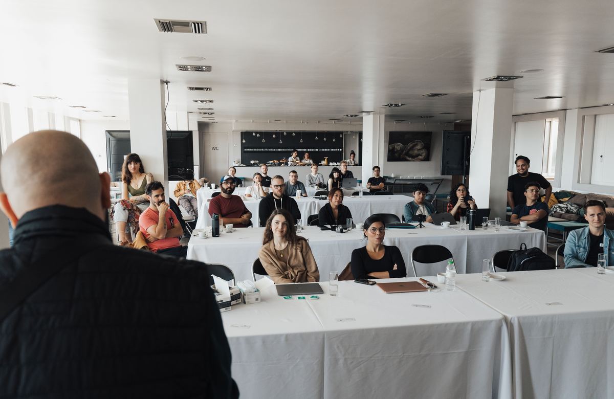 A seminar room seen from behind the speaker, with the audience seated at tables